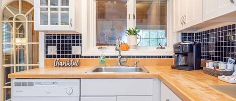 A modern kitchen with a wooden countertop, a built-in dishwasher, and a coffee maker.