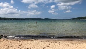 Una playa con agua cristalina, una orilla arenosa y colinas al fondo.