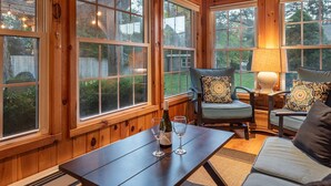 Una habitación acogedora de madera con ventanas amplias, una mesa con copas de vino y asientos cómodos.