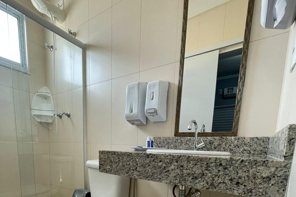 Ein Badezimmer mit Toilette, Waschbecken, Spiegel, Dusche und Seifenspendern.