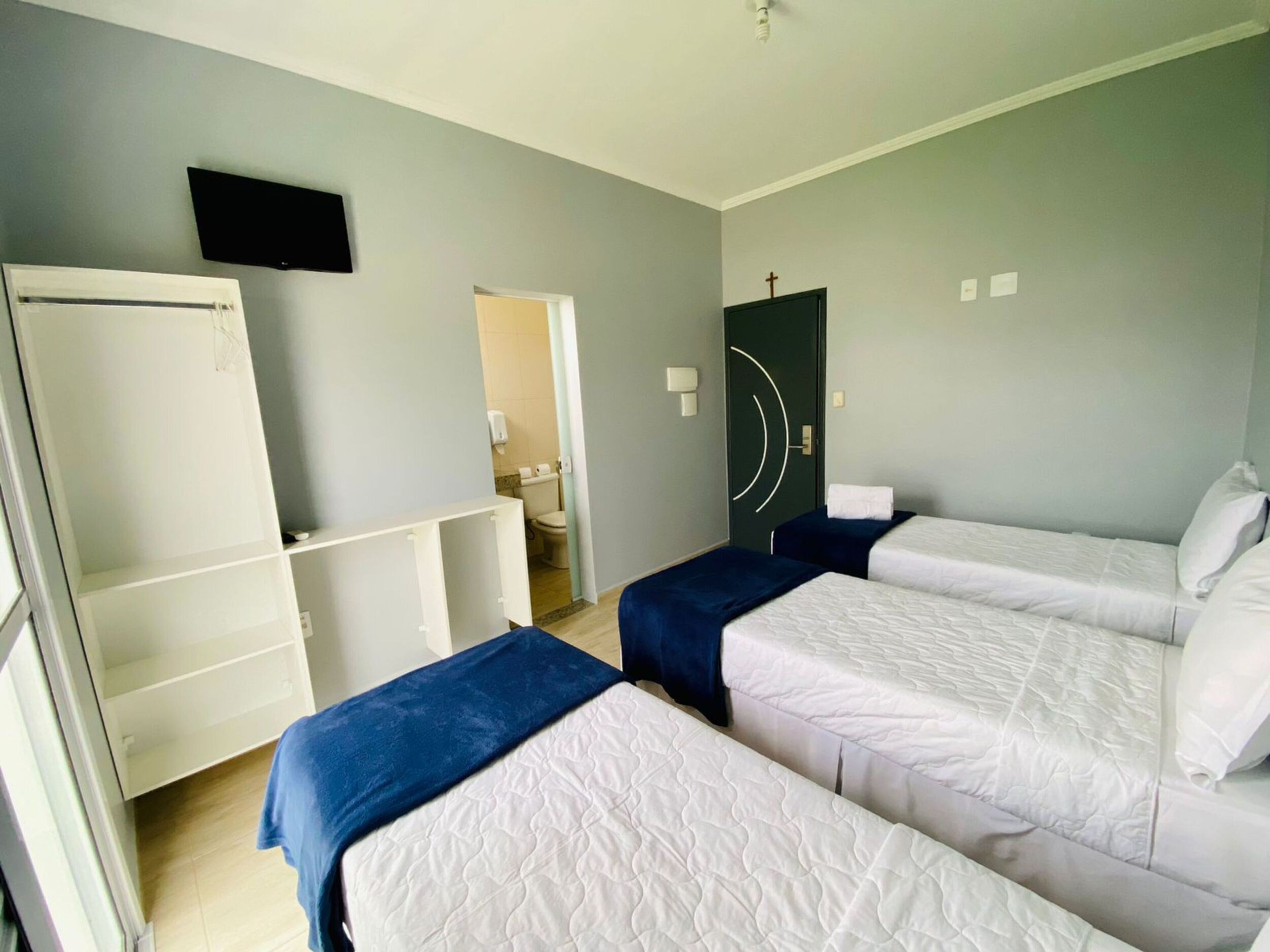 A hotel room with two beds, a television, and a door leading to a bathroom.