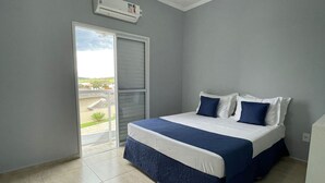 Een slaapkamer met een bed, een schuifdeur naar een balkon en een airconditioner.