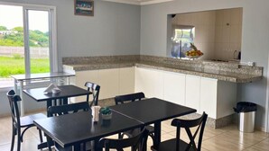Een keuken met een granieten aanrecht, witte kasten en een eethoek met een tafel en stoelen.