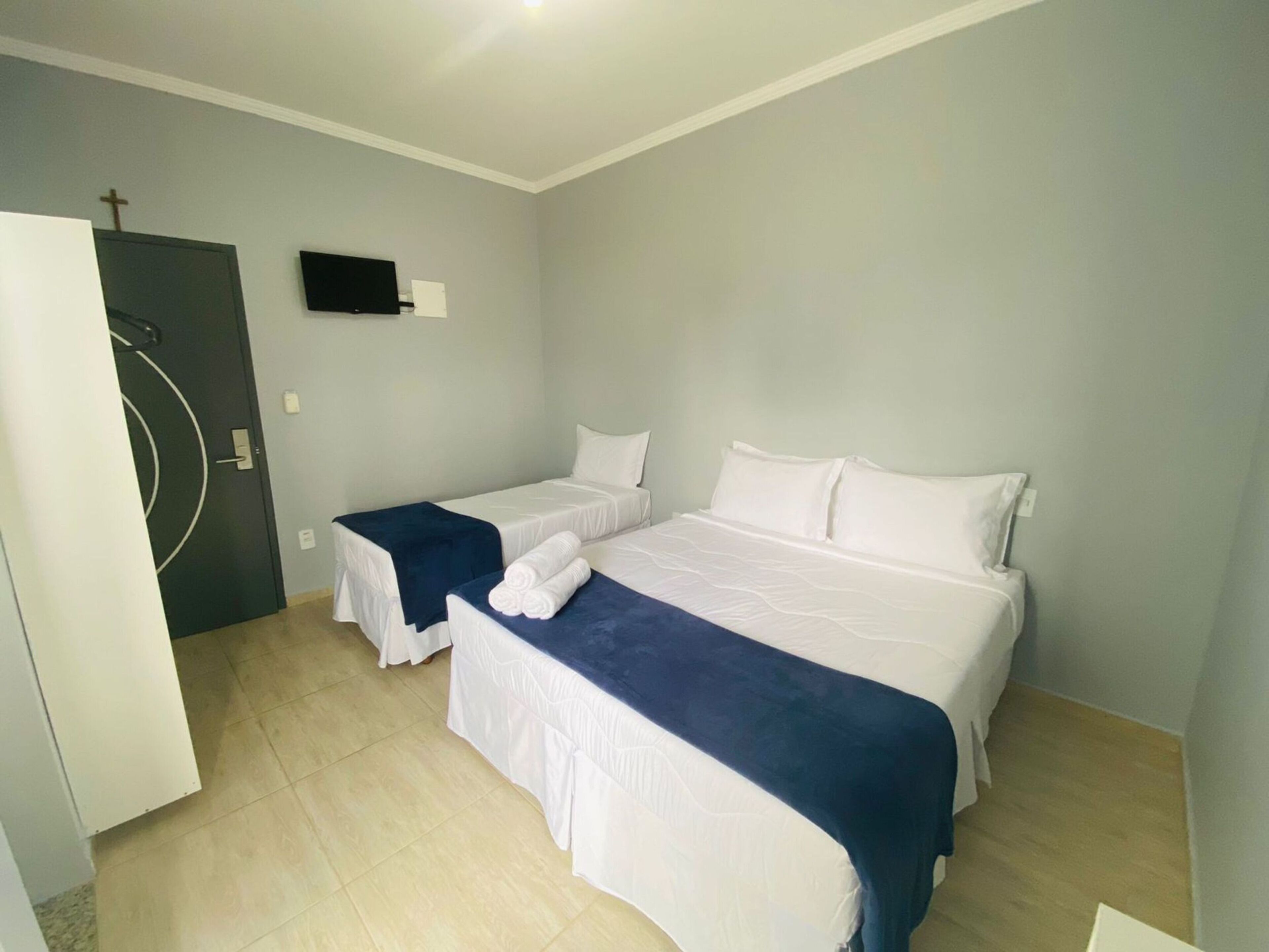 A hotel room with two beds, a flat-screen TV mounted on the wall, and a door with a circular design.