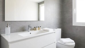 A modern bathroom with a white vanity, a large mirror, and a toilet. - Manchester & Salford | 1BED Apartment with Parking (Salford)