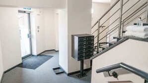 A hotel hallway with a staircase, a mail drop box, and a door leading to another room. - Manchester & Salford | 1BED Apartment with Parking (Salford)