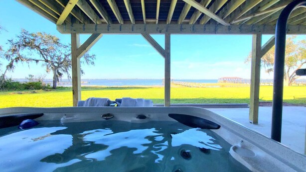 Ein Whirlpool unter einer Holzpergola mit Blick auf Strand und Meer.