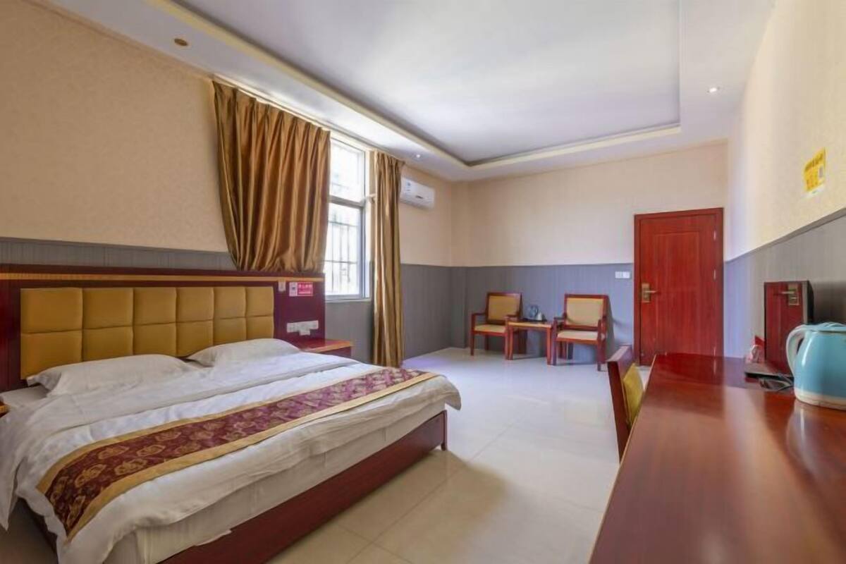 Een hotelkamer met een bed, een bureau, twee stoelen en een televisie.