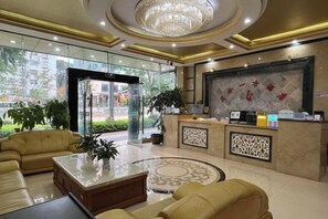 Un vestíbulo de hotel con mostrador de recepción, zona de estar y una araña de cristal.