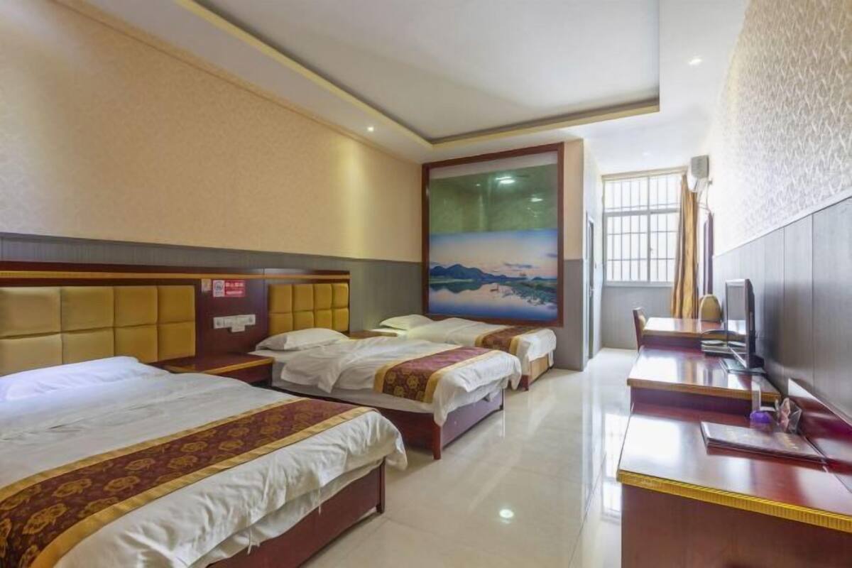 Een hotelkamer met twee bedden, een bureau, een televisie en een schilderij aan de muur.