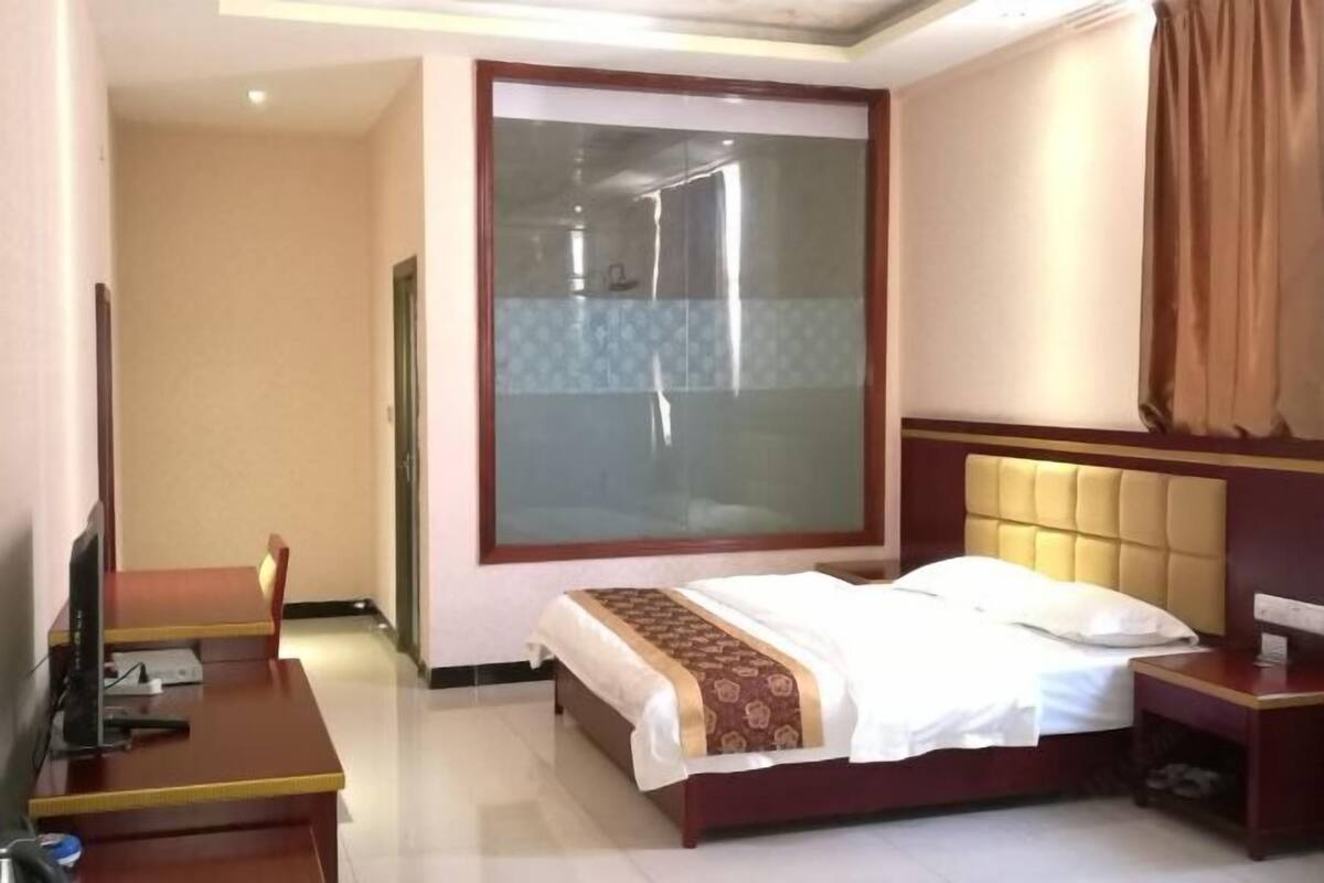 Een hotelkamer met een bed, een bureau, een televisie en een groot raam.