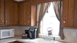 A kitchen with wooden cabinets, a white microwave, a coffee maker, and a sink.