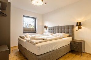 A bedroom with a bed, bedside tables, a window, and wall-mounted lights.