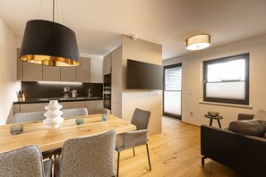 A modern kitchen with a dining area, a sofa, and a TV.