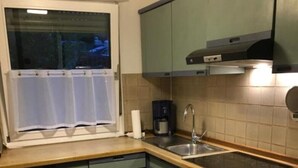 Una cocina compacta con ventana, cafetera, lavamanos y estufa.