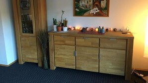 Un gabinete de madera con puertas de vidrio, un cuadro de un edificio y una fila de jarrones decorativos.