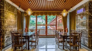 Comedor con techo de madera, paredes de mármol y vista a un edificio rojo exterior.