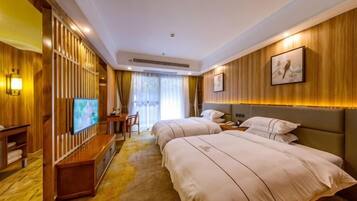A hotel room with two beds, a desk, a TV, and a large window.
