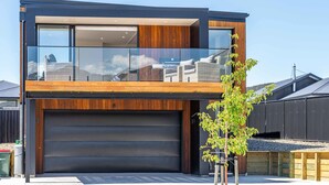 A modern two-story house with a large garage, wooden paneling, and large windows.