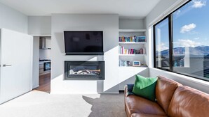 A modern living room with a fireplace, a television, and a bookshelf.