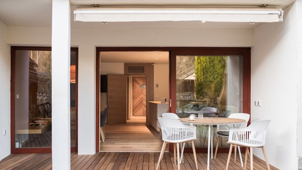 A wooden deck with a table and chairs, a sliding glass door, and a view of the outdoors. - Luxury gateway in Kranjska gora (Jesenice)