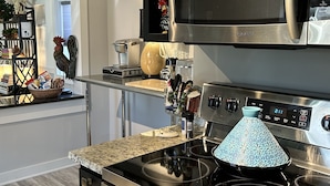 Una cocina moderna con electrodomésticos de acero inoxidable, encimera de granito y una tagine marroquí decorativa sobre la hornilla.