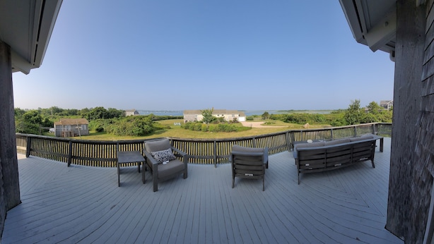 Une terrasse dotée de mobilier d’extérieur, offrant une vue sur le paysage et agrémentée d’une rambarde en bois.