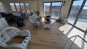Une pièce spacieuse avec de grandes fenêtres, des meubles en osier et un coin repas.