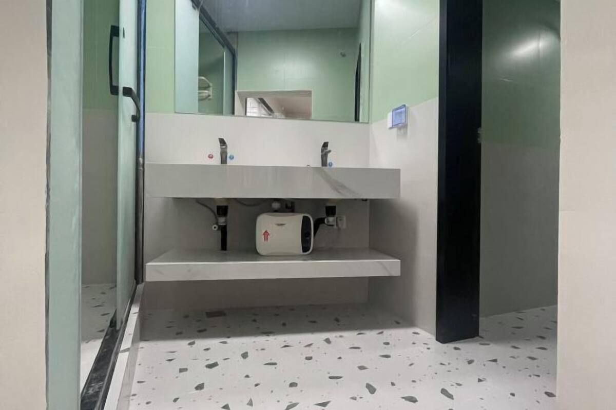 A bathroom with a white sink, a mirror, and a towel dispenser.