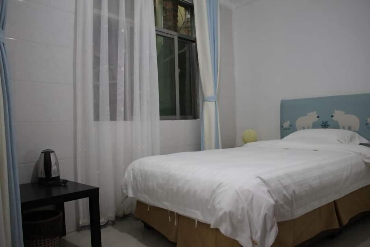 A bedroom with a bed, a nightstand, a window with curtains, and a wall with a sheep design.