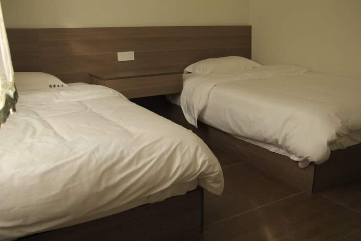 Two single beds with wooden headboards in a room with tiled flooring.