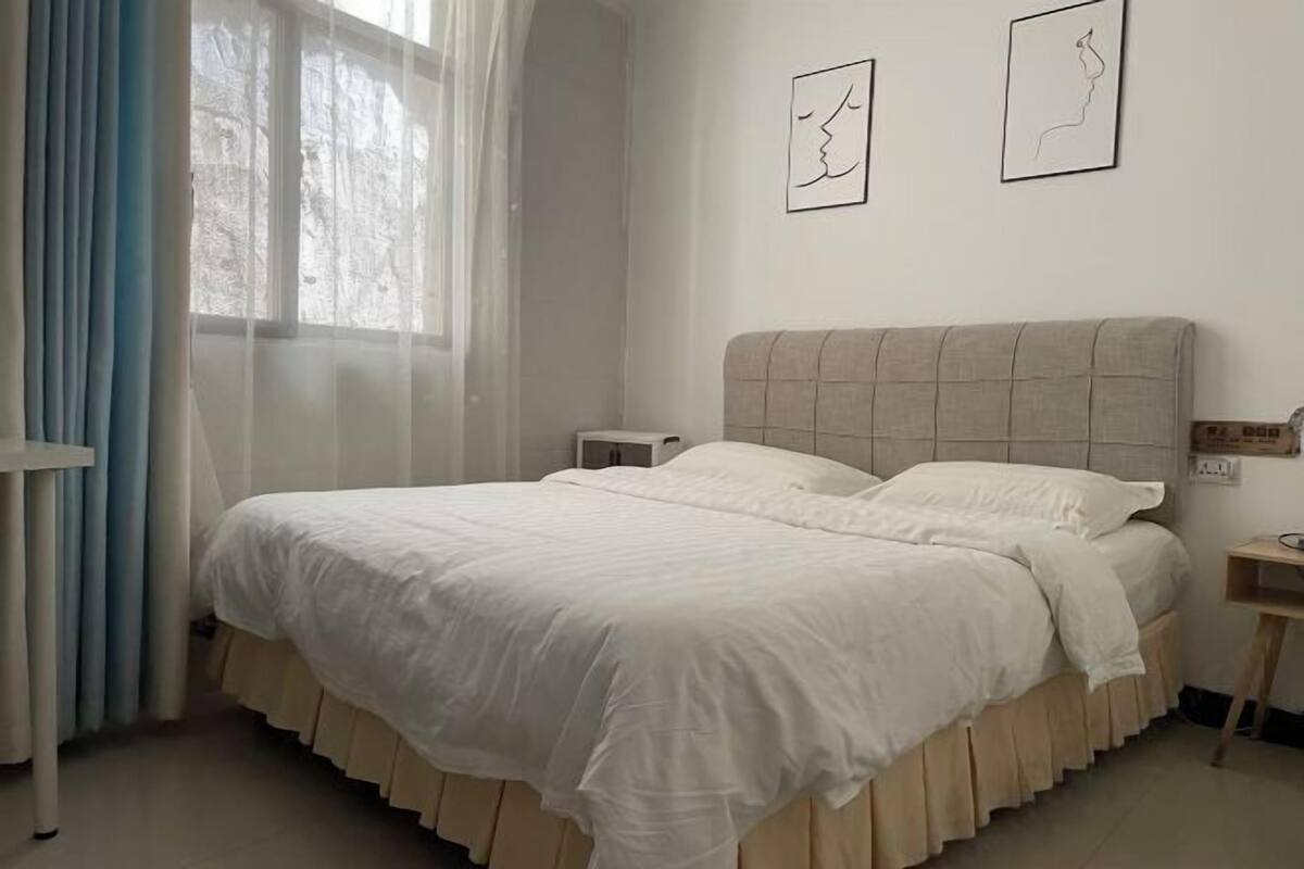 A neatly made bed with a white duvet, a wooden headboard, and a bedside table with a lamp.