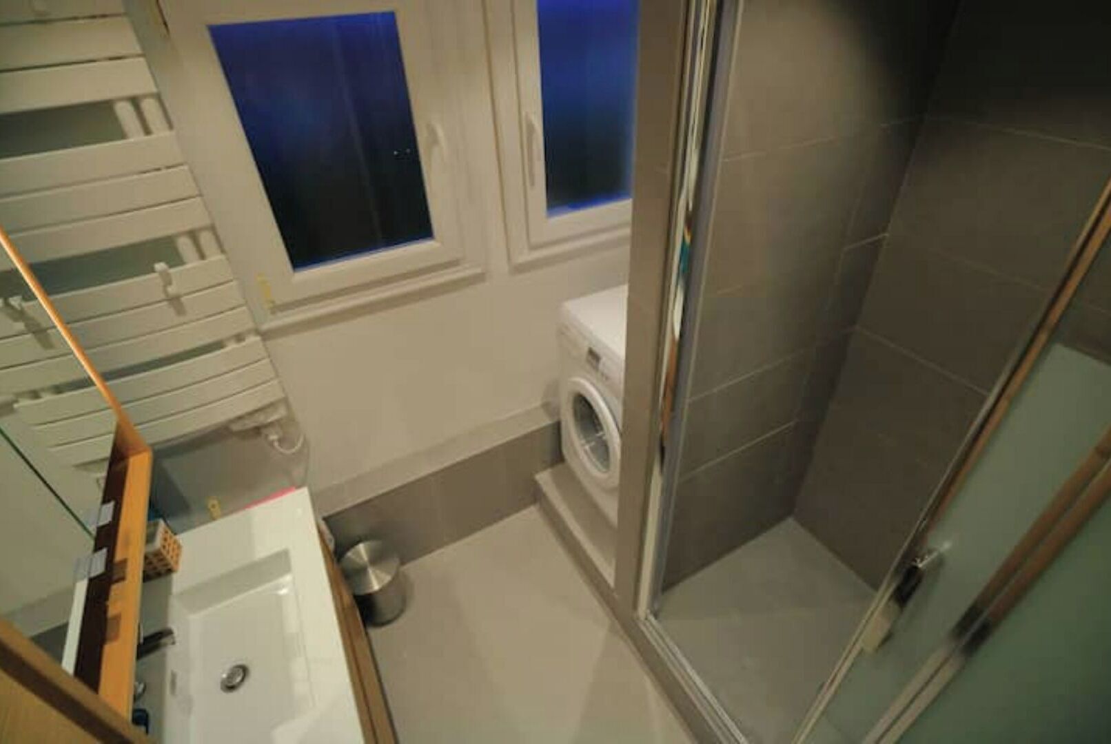 Une petite salle de bain comprenant une douche, des toilettes et un lave-linge.