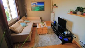 Un soggiorno con un divano, un tavolino, una TV e un quadro appeso al muro.