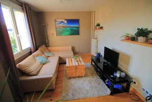 Ein Wohnzimmer mit einer Couch, einem Couchtisch, einem Fernseher und einem Gemälde an der Wand.