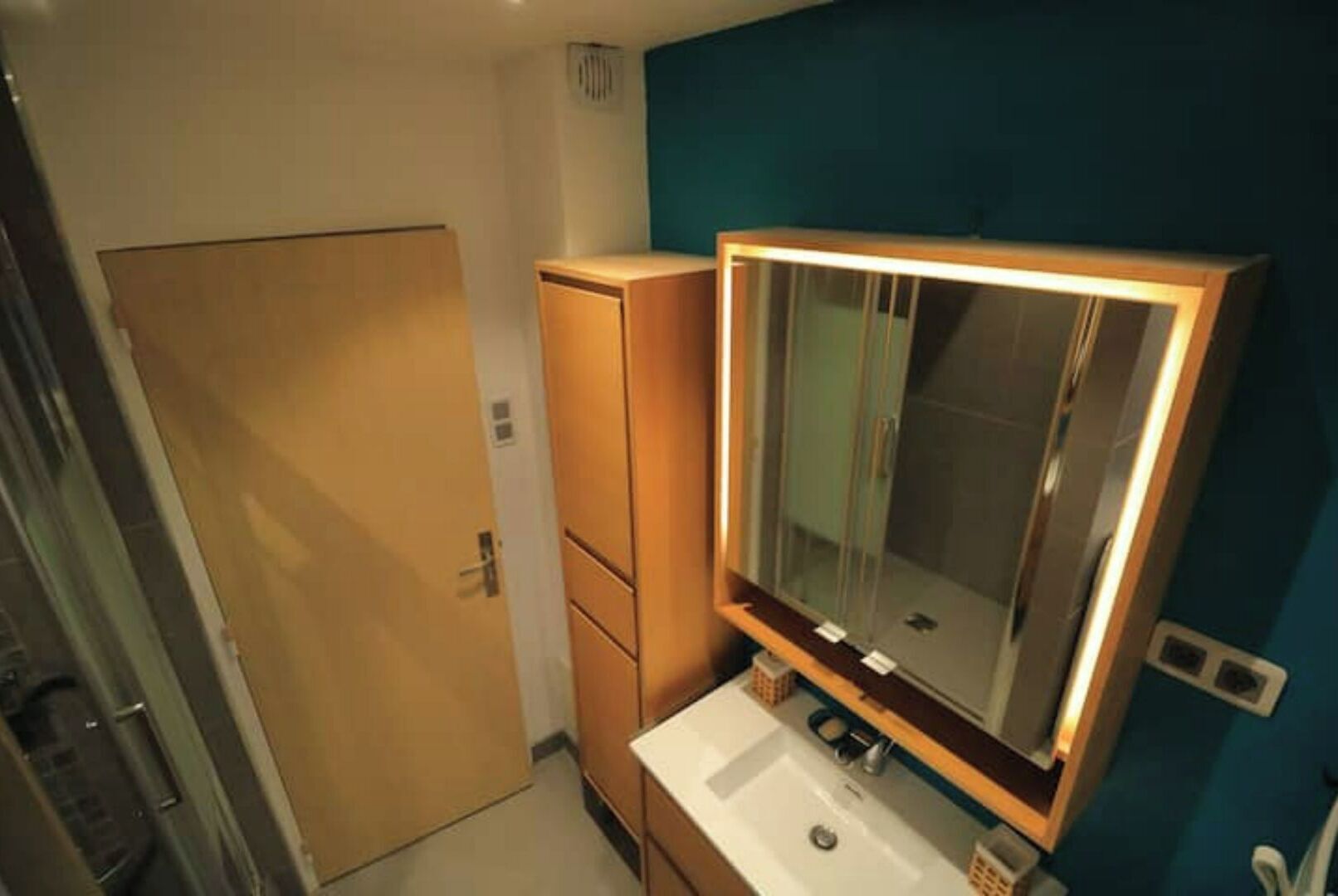 Une petite salle de bain avec un lavabo blanc, un miroir et un meuble en bois.