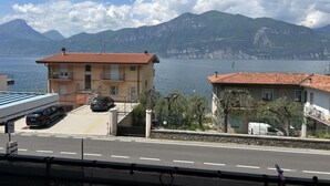 Une route côtière bordée de bâtiments, un ciel dégagé et des montagnes en arrière-plan.