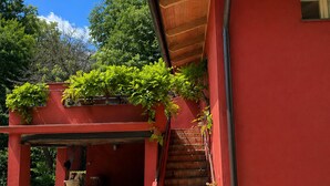 Un edificio rojo con una escalera de madera, un porche cubierto y un camino de entrada de grava.