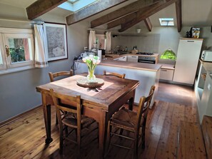 Una cucina rustica con travi in legno, un tavolo da pranzo con sedie e vista all'esterno.