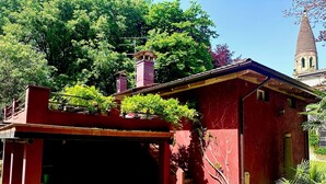 Un edificio rojo con un porche cubierto y una torre al fondo.