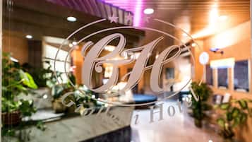 A hotel reception area with a glass window displaying the hotel's name.