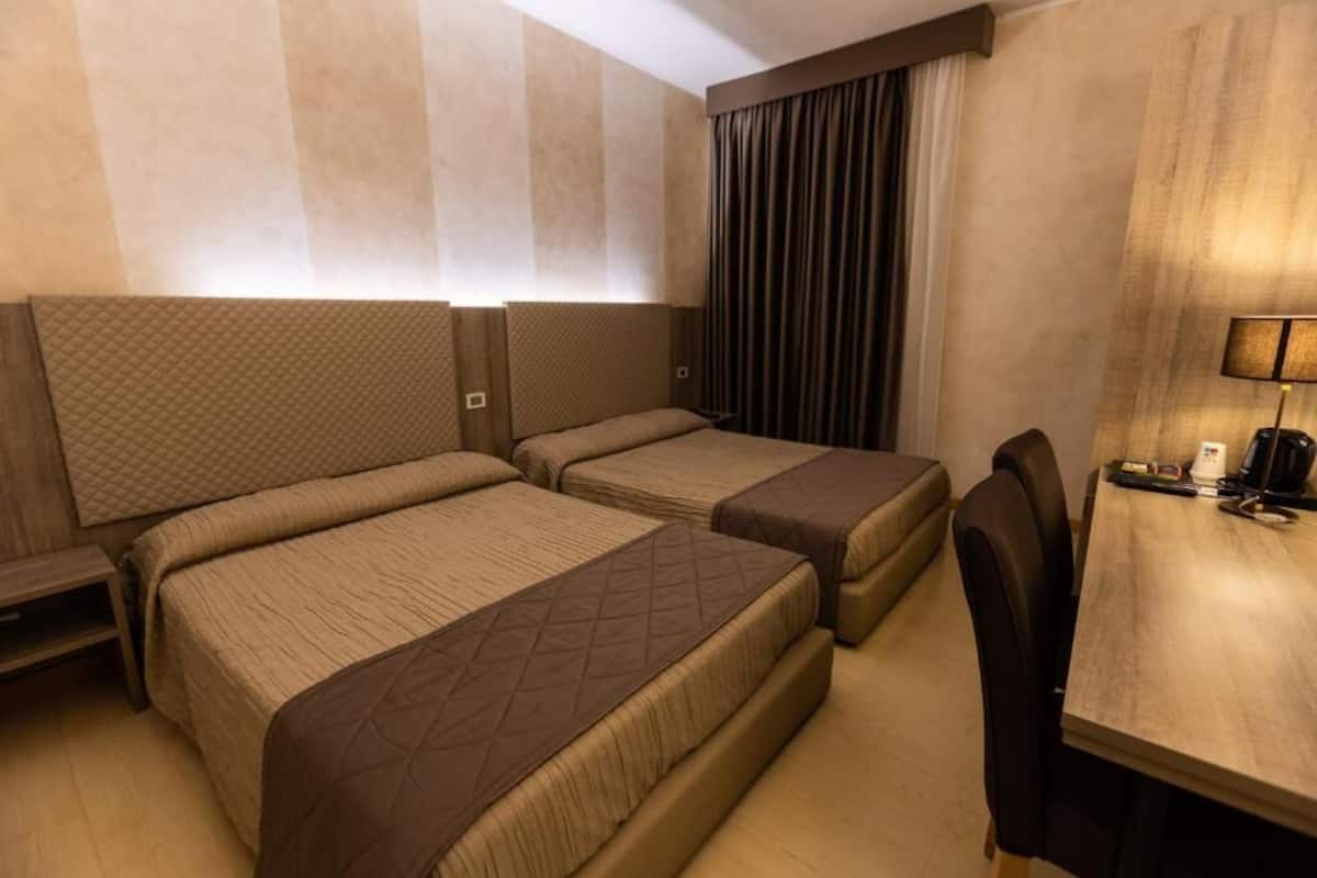 A hotel room with two beds, a desk, and a chair.