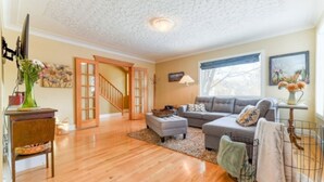 A living room with hardwood flooring, a grey sofa, a coffee table, and a staircase leading to another room. - First Place-Family Corporate Social Gatherings
Home Away From Home. Pet Friendly (Strathmore)