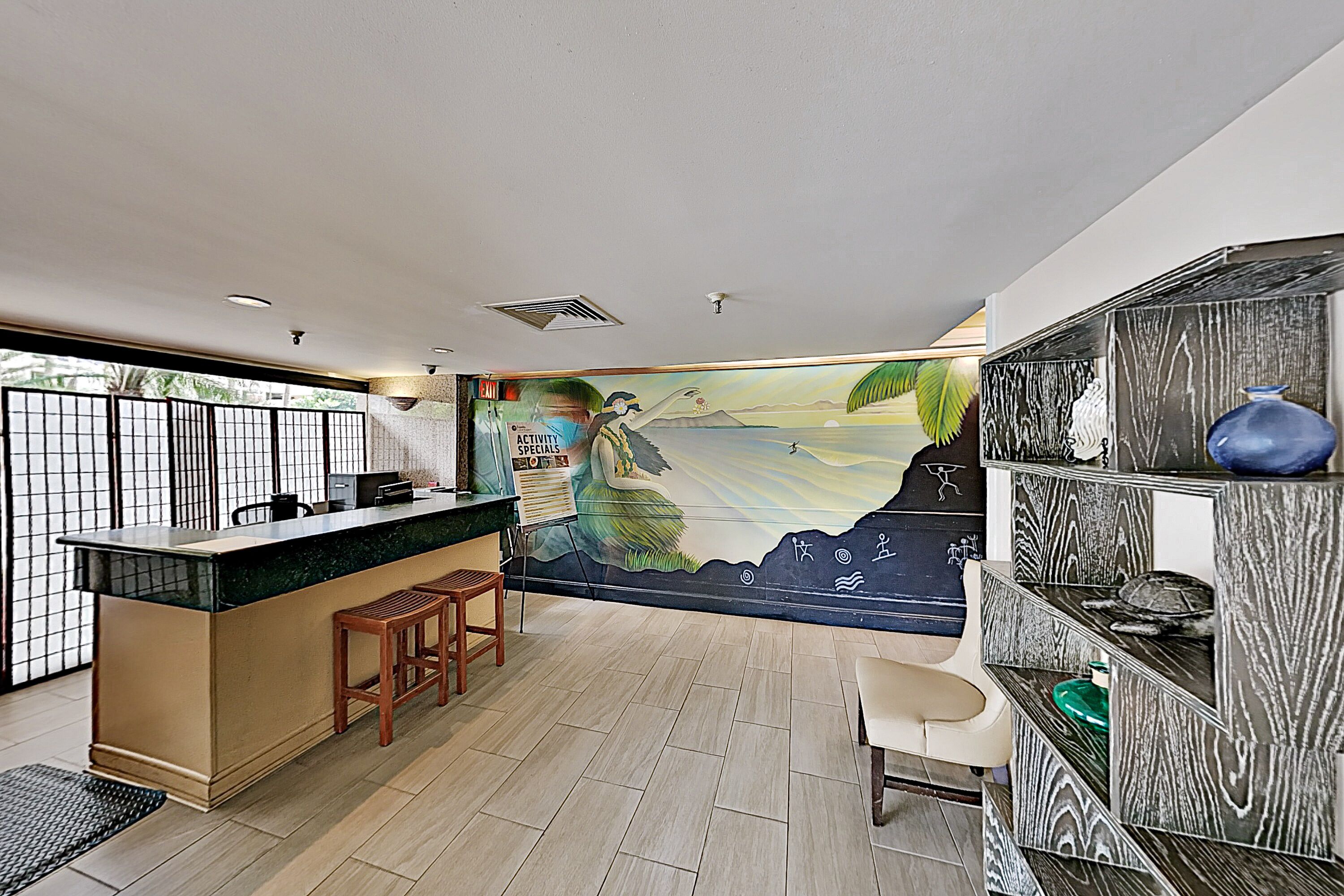 A modern kitchen with a bar area, a mural on the wall, and a wooden floor.