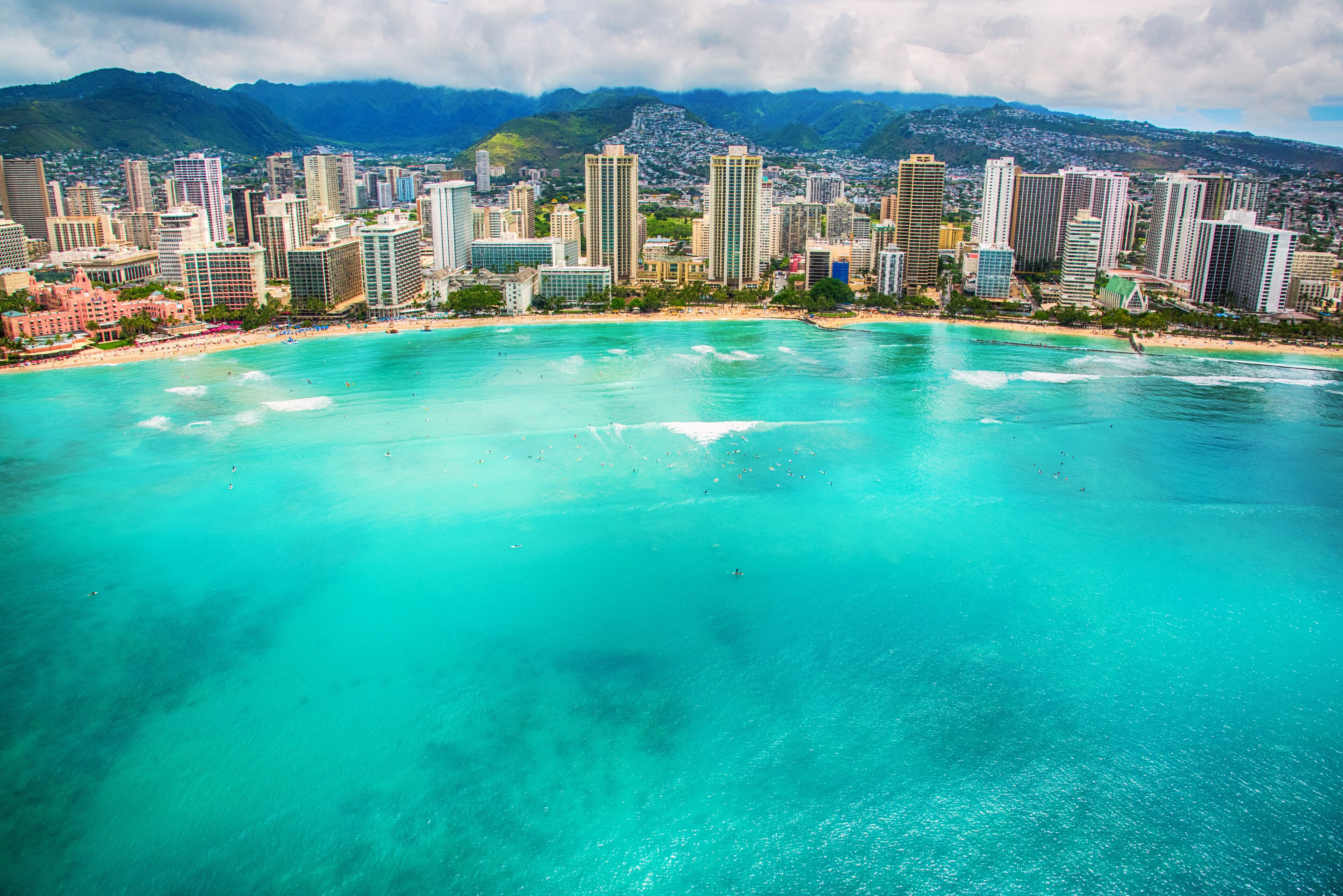Un paysage urbain côtier avec de hauts immeubles et une plage aux eaux turquoise.