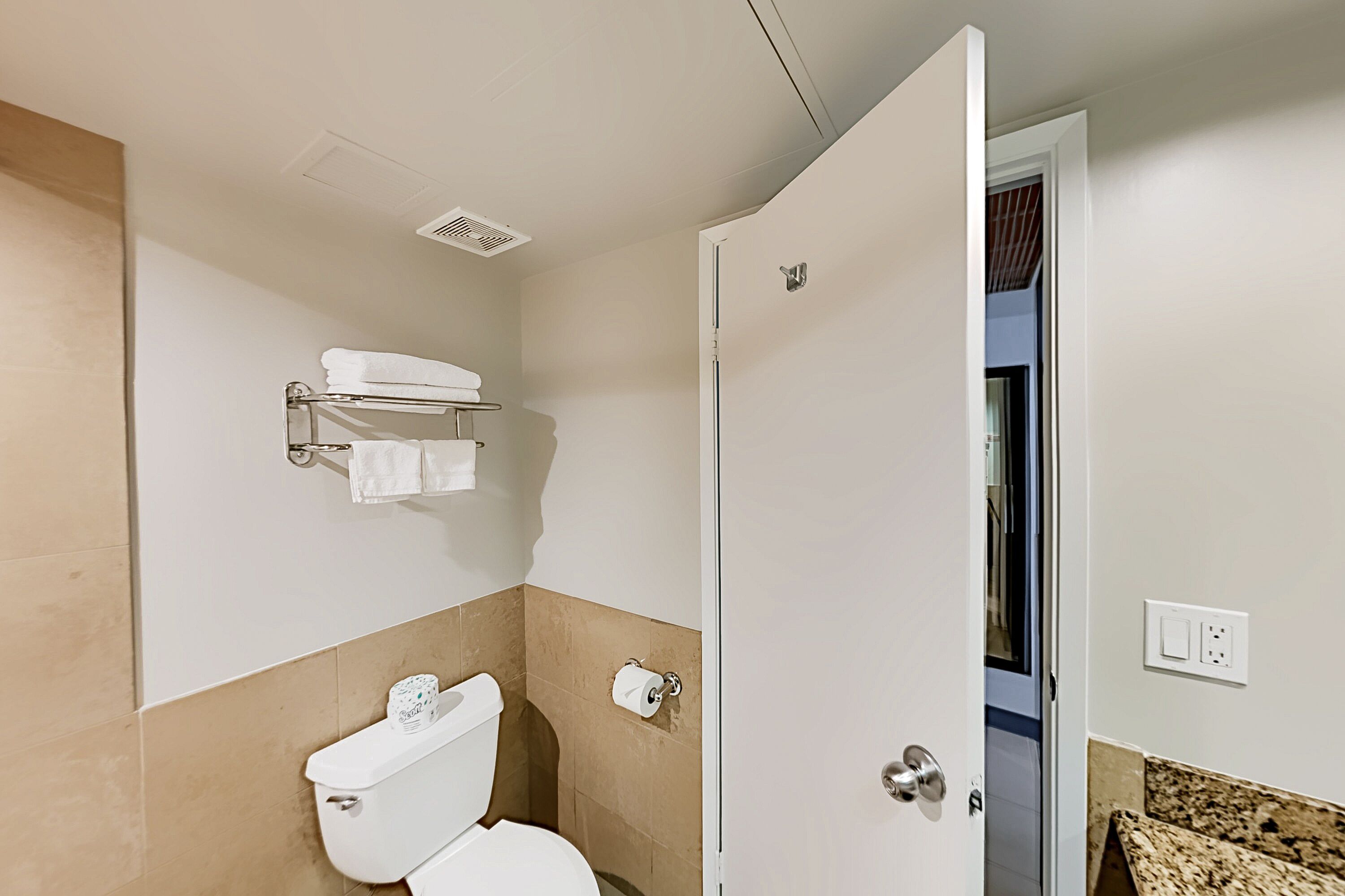 A bathroom with a toilet, towel rack, and a shower door.