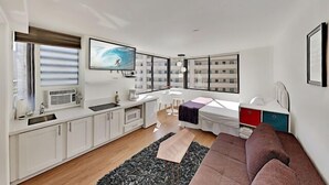 Ein modernes, kompaktes Wohnzimmer mit einer Küchenzeile, einem Essbereich und einem Schlafzimmer.