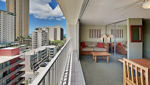 Un balcón con vistas a edificios altos, un sofá, una mesa y una lámpara.
