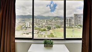 A room with a large window overlooking a cityscape with buildings and mountains. - Quaint Waikiki Monarch Studio | Pool + Gym (Honolulu)
