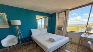 A hotel room with a bed, a desk, a chair, and a large window with a view of the landscape. - Updated! Humble Hawaiian Monarch Studio | Pool (Honolulu)